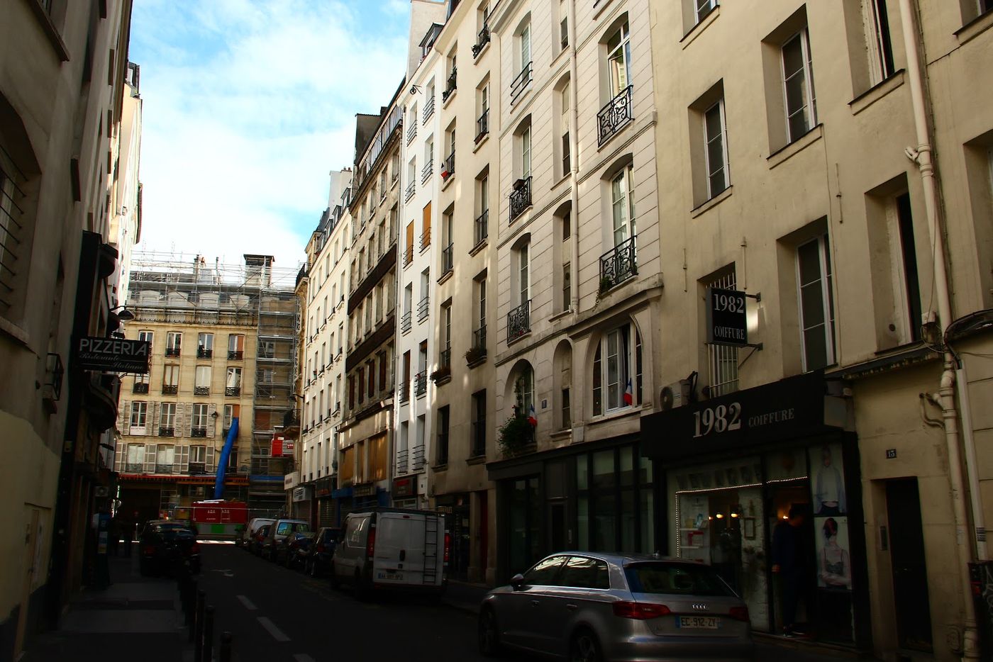 La rue du Ponceau et ses immeubles crème, l’enseigne 1982 Coiffure à droite.